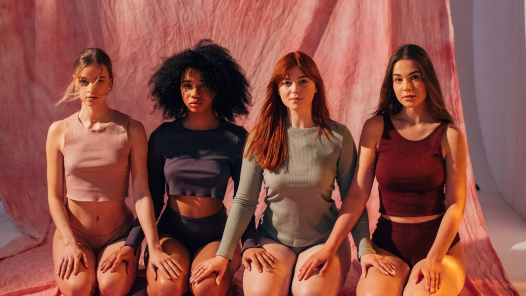 Vier junge Frauen unterschiedlicher Rasse sitzen nebeneinander