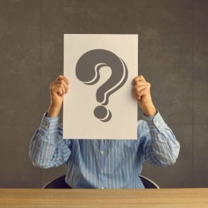 Webdesign Göttingen. Frau hält ein Plakat mit einem Fragezeichen vor ihrem Gesicht