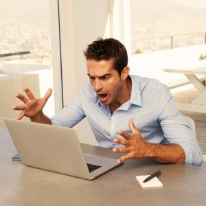 Webdesign Göttingen. Mann regt sich vor dem Laptop auf.